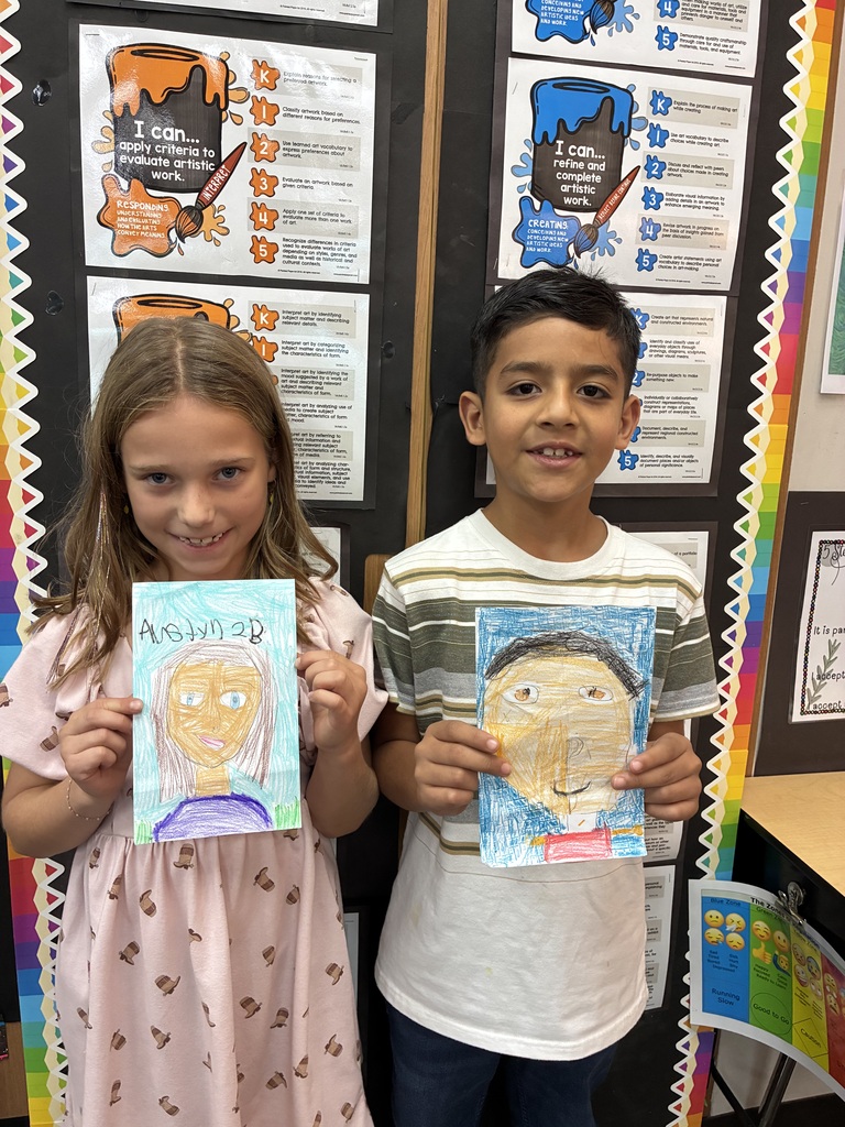 Students holding drawing of themselves