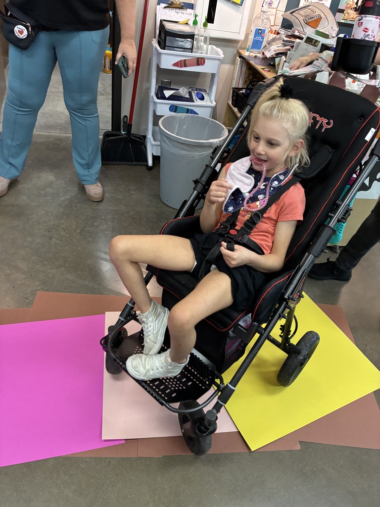 girl in wheel chair going over pink and yellow papers