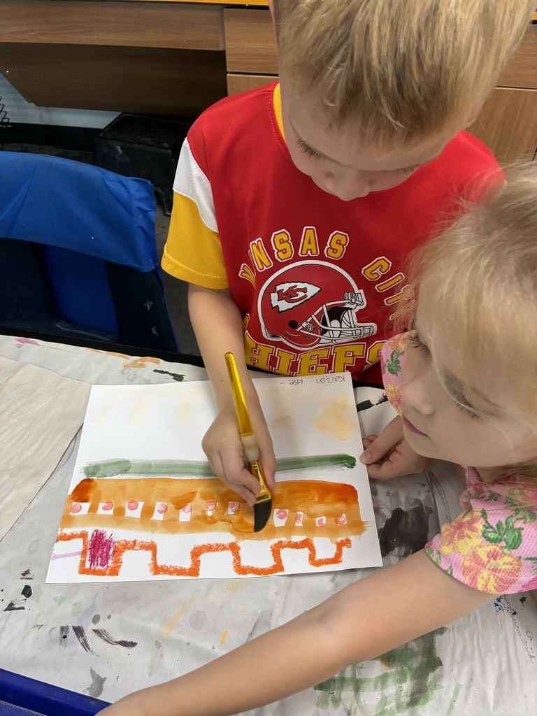 Kindergarten students with paintbrushes painting lines and colors.