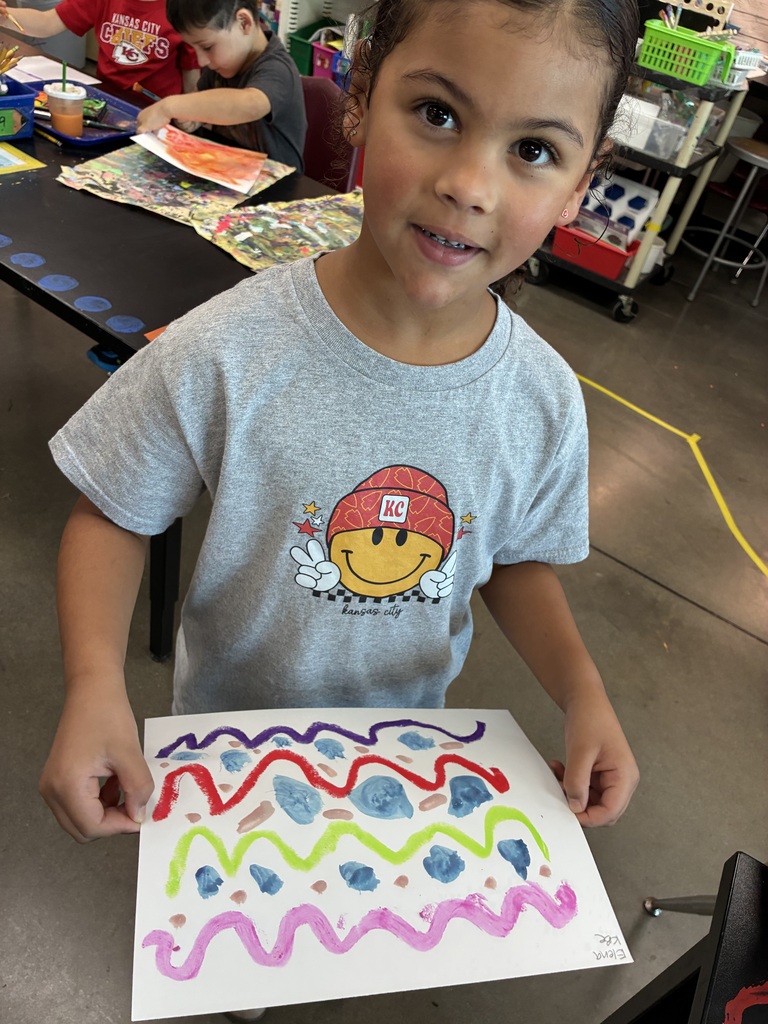 Kindergarten student showing her painting of lines and colors.