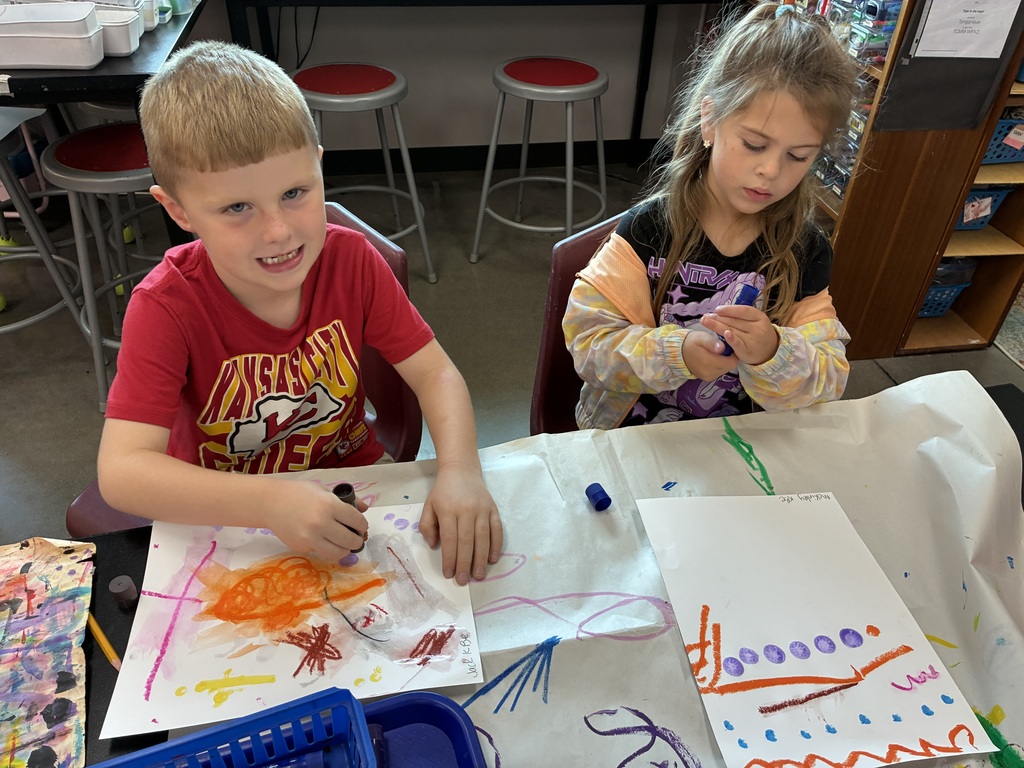 Kindergarten students with paint sticks painting lines and colors.