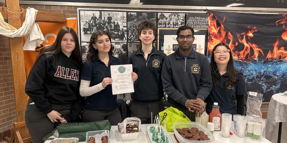 Students posing behind a table with treats on it.