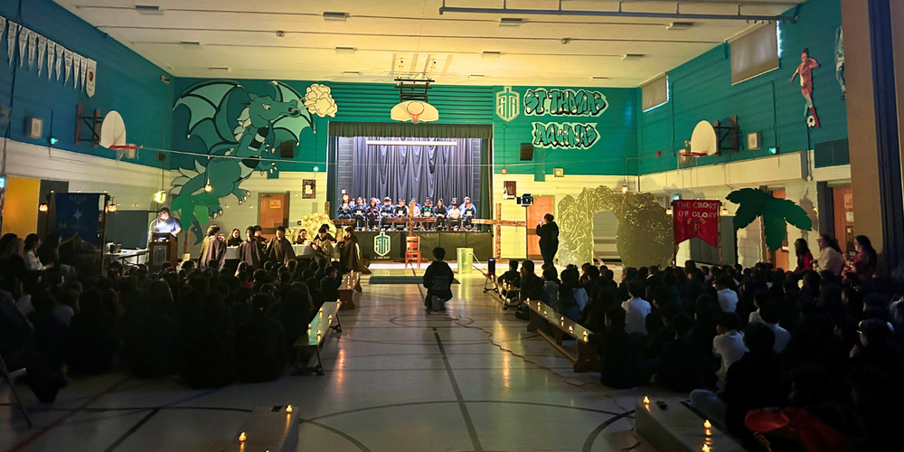 A large group of students in a gym watching a play. 