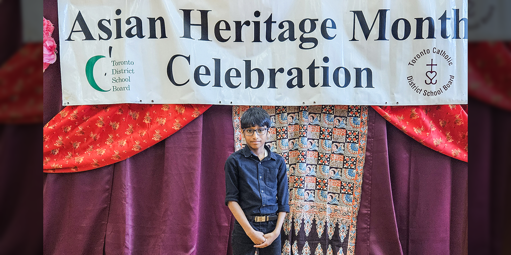 Photo of Evan standing in from of a banner that says Asian Heritage Month Celebration