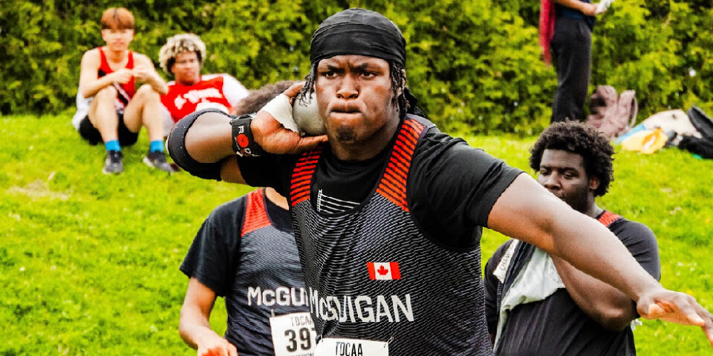 Photo of Eghosa on the field getting ready to throw a shotput