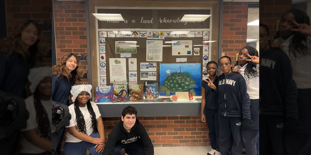 Photo of St. Angela students posing with the Land Acknowledgement display that they created