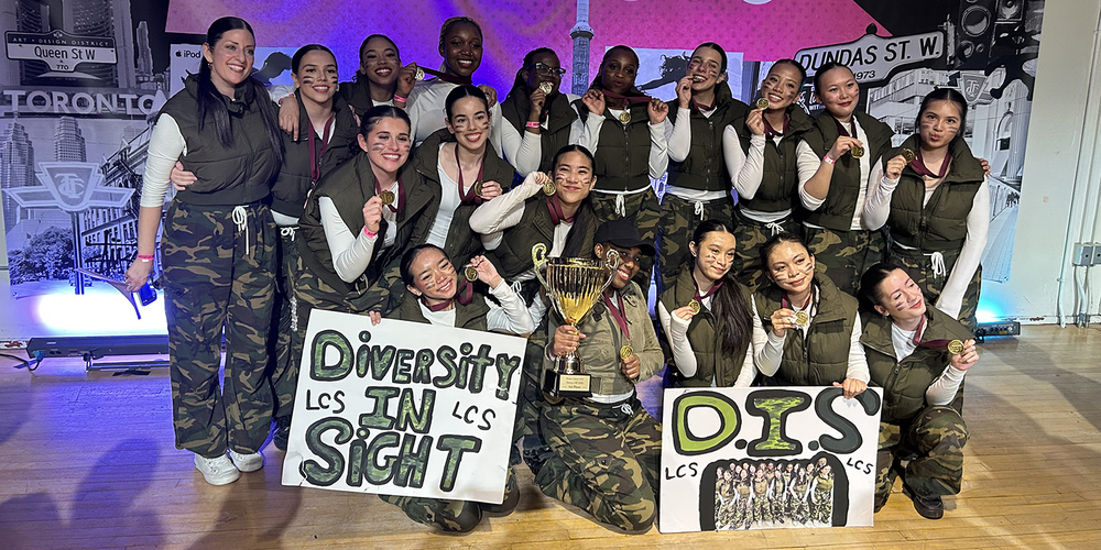 Group photo of the Dance Team with their team banners and championship trophy and medals