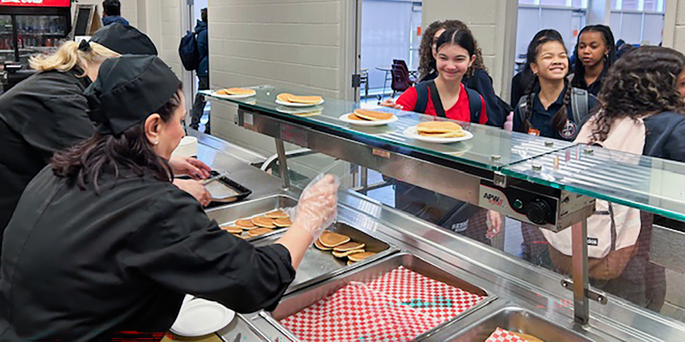 Photo of Redmond students being served pancakes by the staff