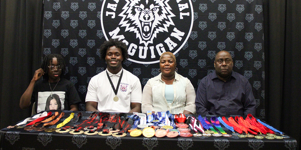 Eghosa at the signing with his family, with all his medals laid out in front of him