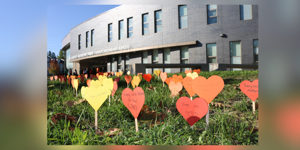 The front of St. Joseph's Morrow Park Catholic School with paper hearts planted in the front garden.