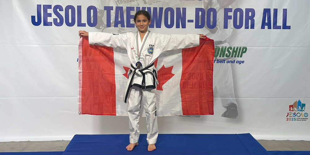Photo of Leianna on the podium with her medal holding out the Canada flag behind her