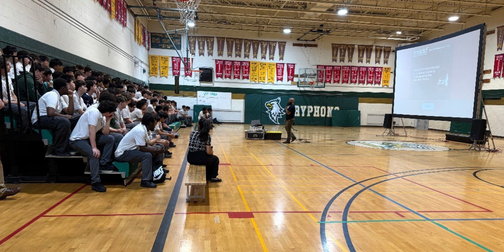 Students watching a presentation in a gym.
