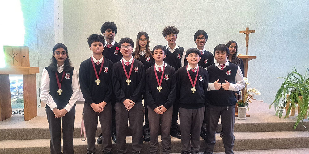 Photo of St. Patrick alter server students standing in front of the alter in their school uniform and wearing their medals