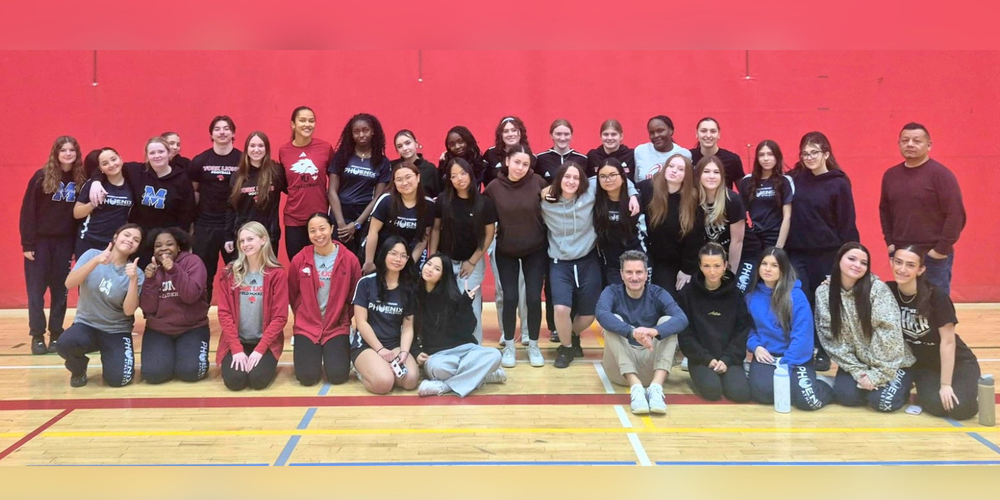 Large group of young women posing in a gym.