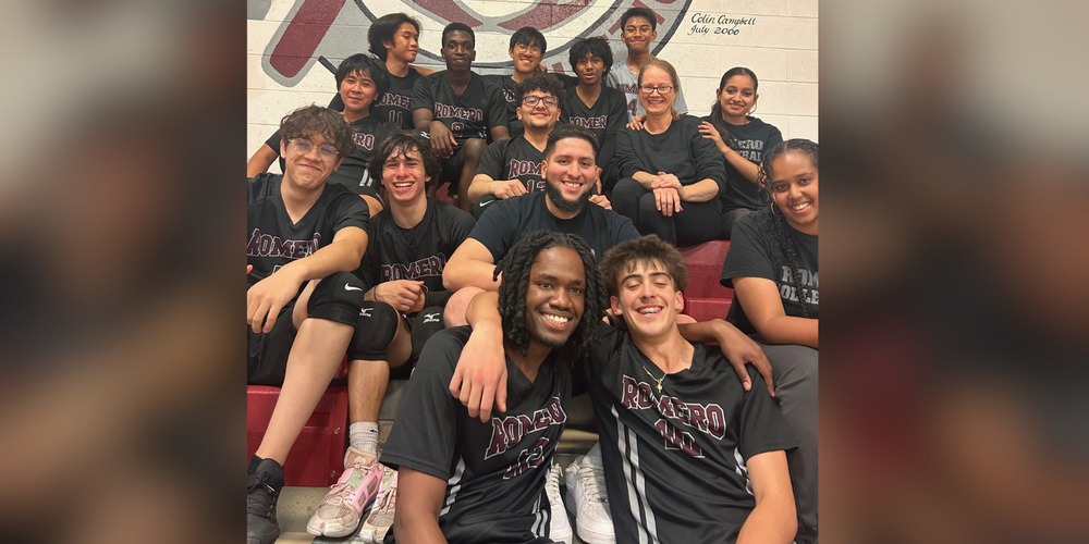 Group photo of students in athletic wear, posing on bleachers.