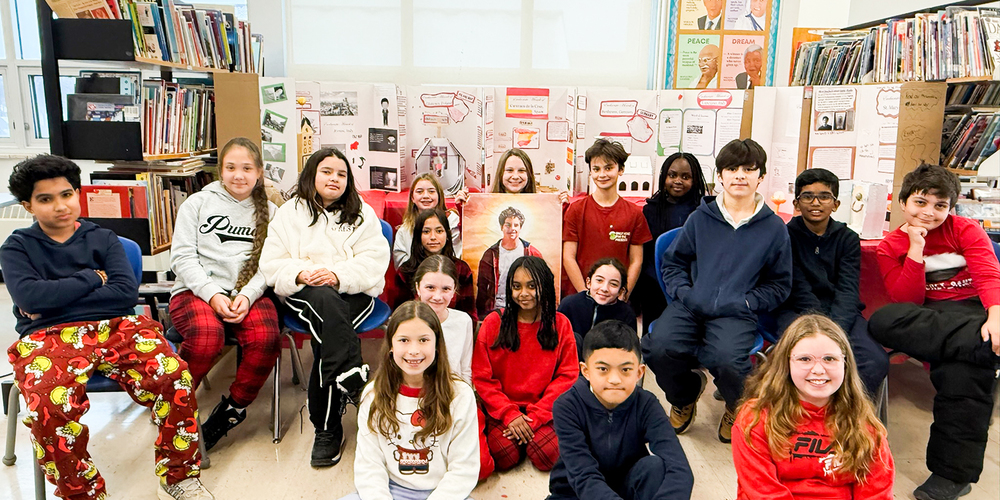 Photo of St. Benedict students in the classroom with their works displayed behind them
