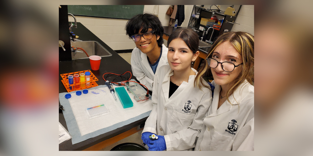 3 students in lab coats working on something scientific
