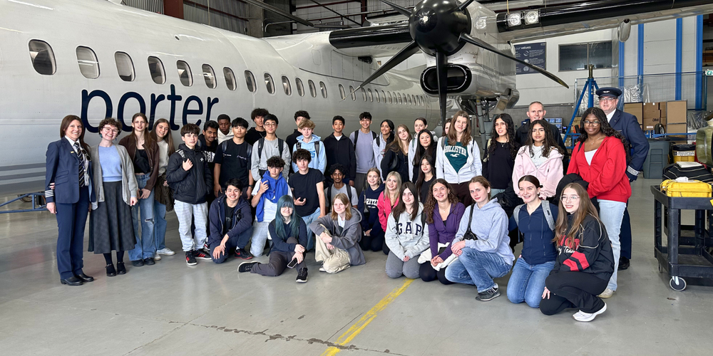 group photo in front of a Porter airplane with pilots