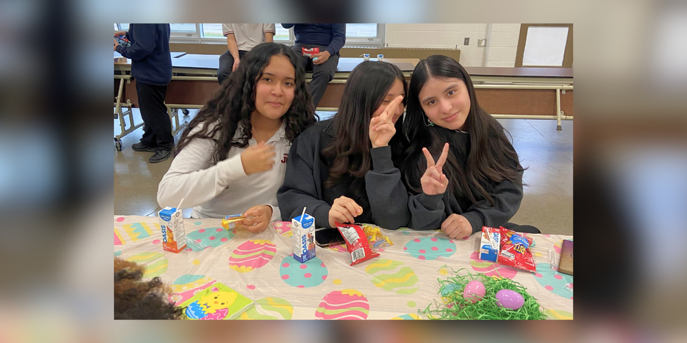 3 students at a table decorated with Easter themed items.