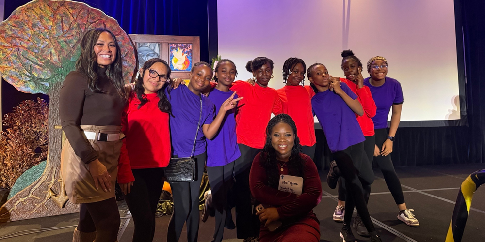 A group of students posing with faculty on a stage.