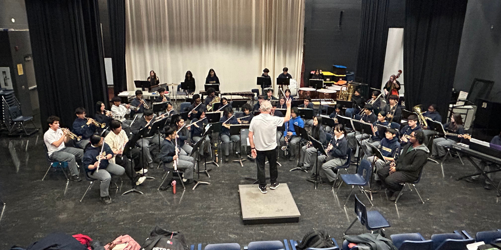 A group of students playing instruments with a conductor in the middle