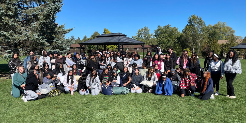 A large group photo of students posing outdoors on a sunny day.