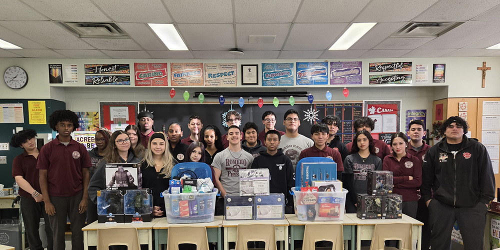 Group photo of St. Oscar Romero students in a classroom with the items that they have collected to donate