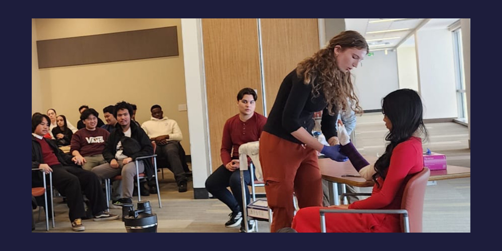 Students in a class watching someone demonstrate putting on a cast