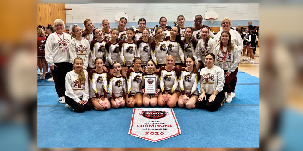 A group of girls sitting in a gym in cheerleading uniforms