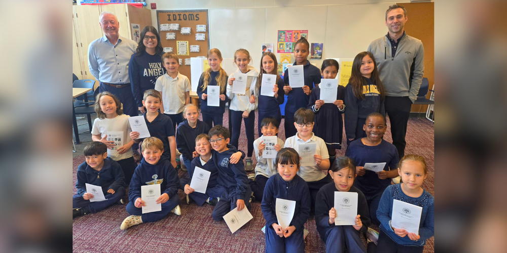 Group of young children in a classroom holding papers. 