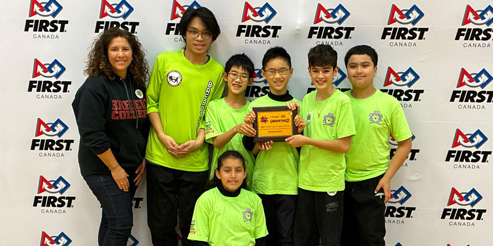 Group photo of robotics team with their award and teacher