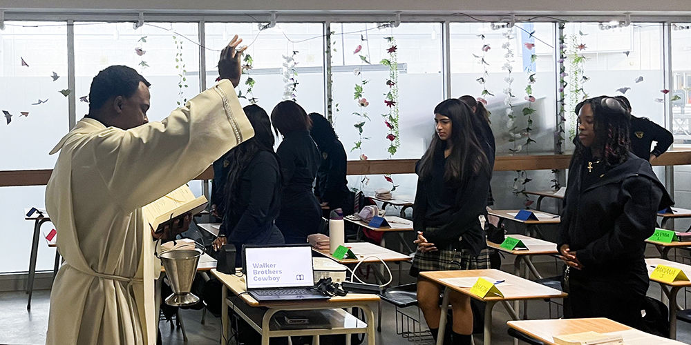 Photo of Father Joseph visiting one of the Loretto College classrooms and the students standing up to listen to him