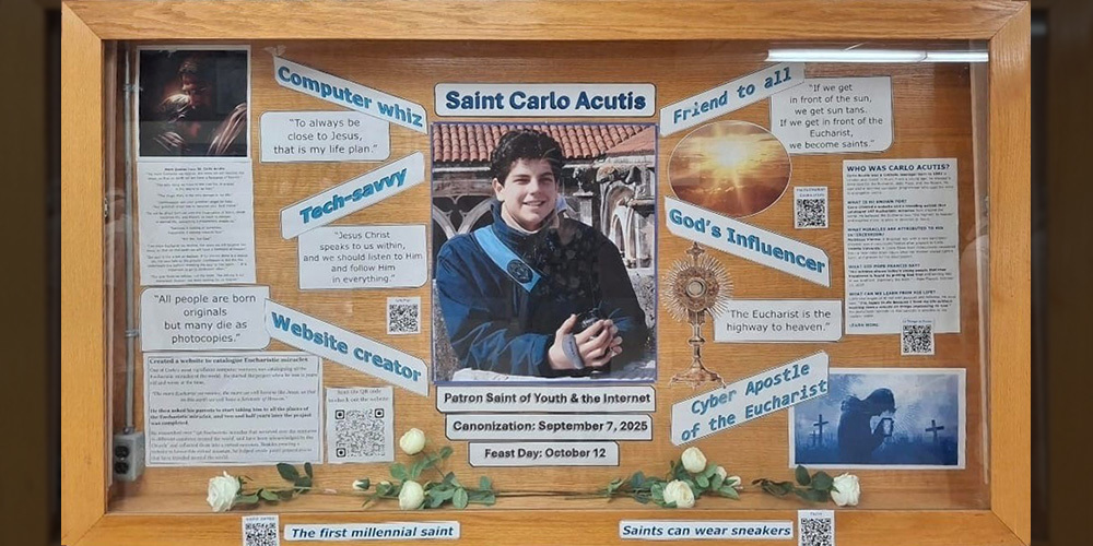 Display board about the life of Saint Carlo Acutis, with a picture of Carlo in the middle, surrounded by informational tidbits about his life