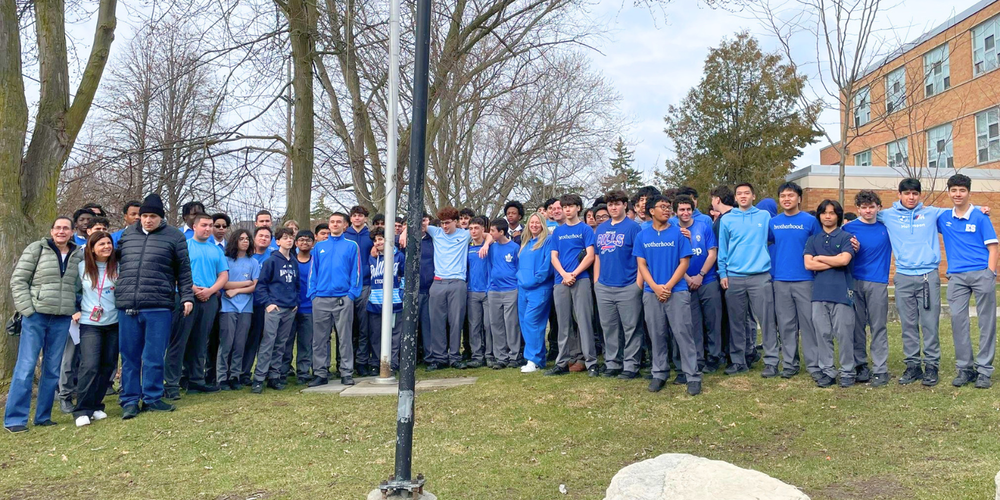 Large group photo of students outdoors wearing blue. 
