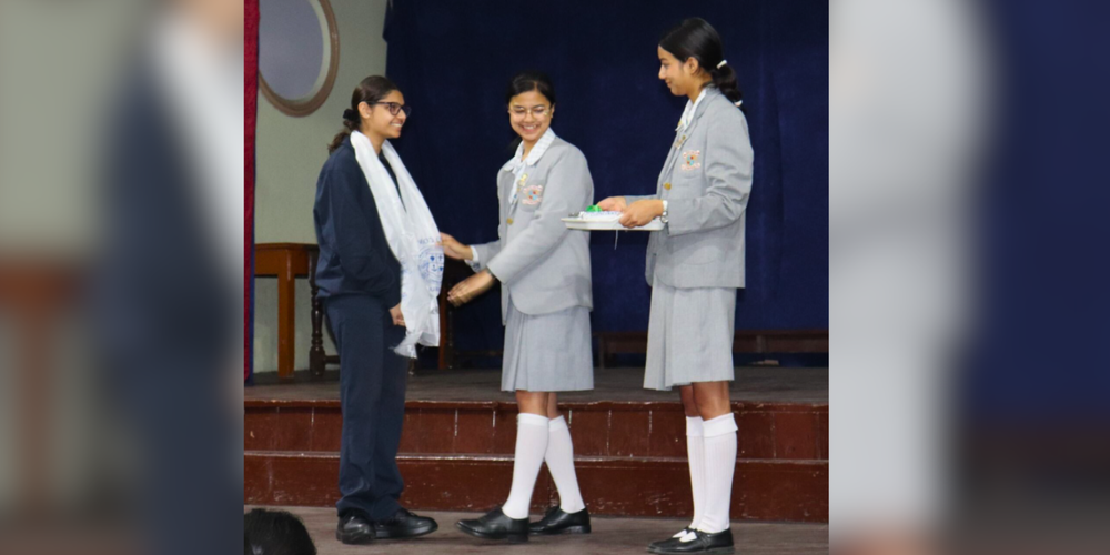 3 girls in uniform on a stage. 