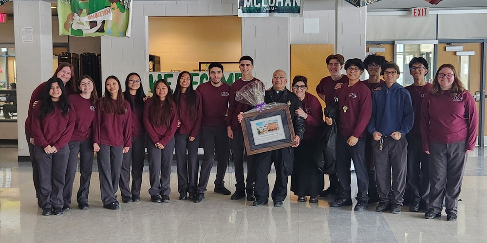 Group photo of students in uniform with a priest