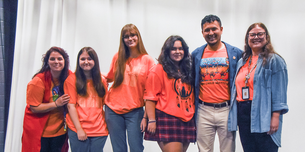 Photo of Redmond students and staff posing with Jason, all of them in Orange shirts
