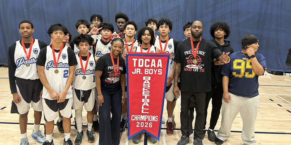 Group photo of SJPII basketball team with their championship banner