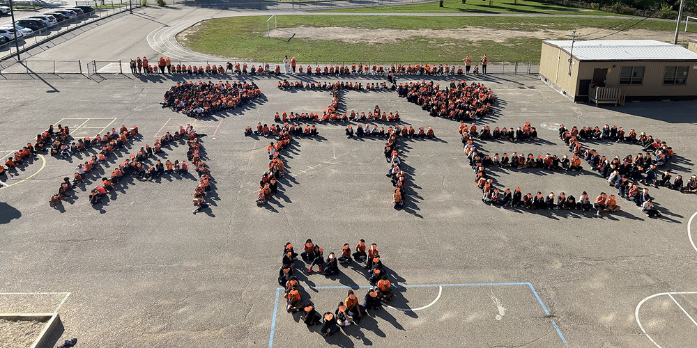 Bird's eye view photo of St. Wilfrid students sitting together with Orange paper in a formation that spells out I Matter in orange accompanied by orange hearts