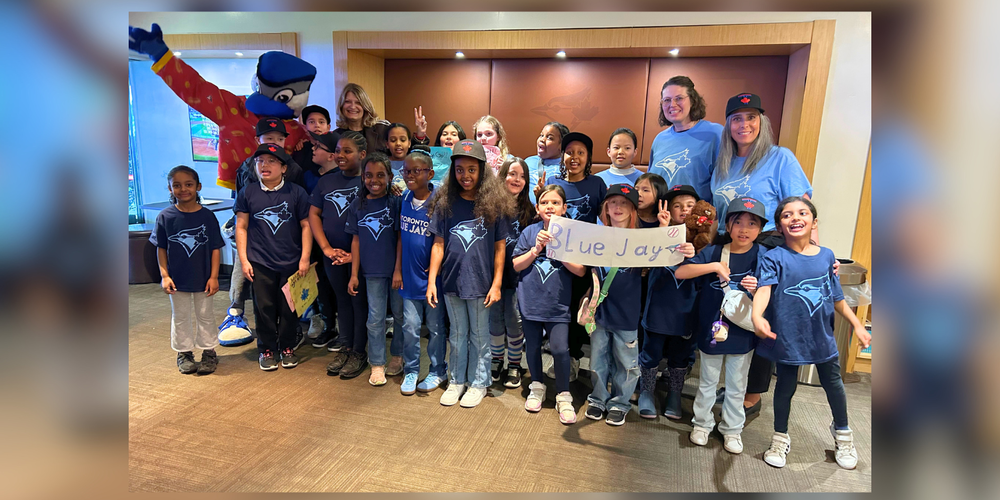 Group photo in blue jays gear, posing with the Blue Jay's mascot. 