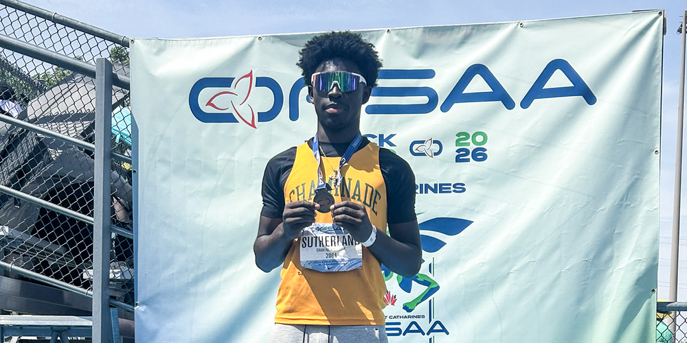 Photo of Jayden on the podium holding his gold medal and wearing his yellow Chaminade jersey