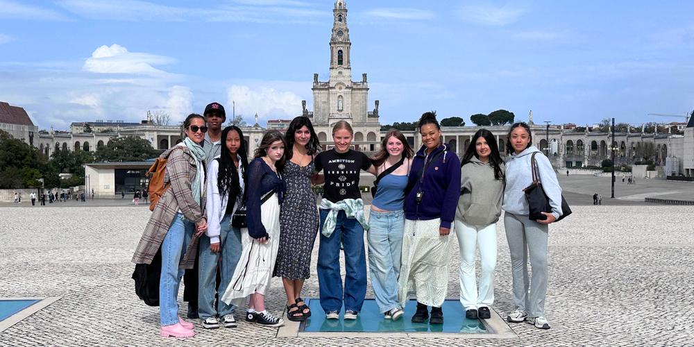 Group of teens with an adult posing outdoors in front of a european background