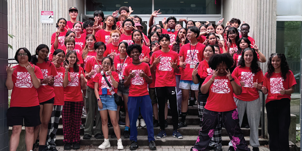 A group of students wearing red t-shirt smiling at the camera.