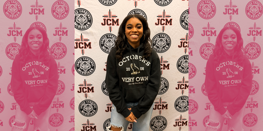 a student posing in front of a JCM Banner