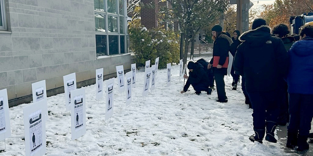 Photo of St. Anthony students planting informative plaques in the ground for Remembrance Day