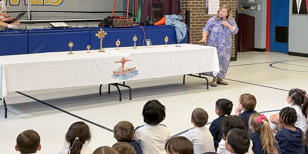 Photo of Mrs. Moon presenting to the lyrics to OLPH students