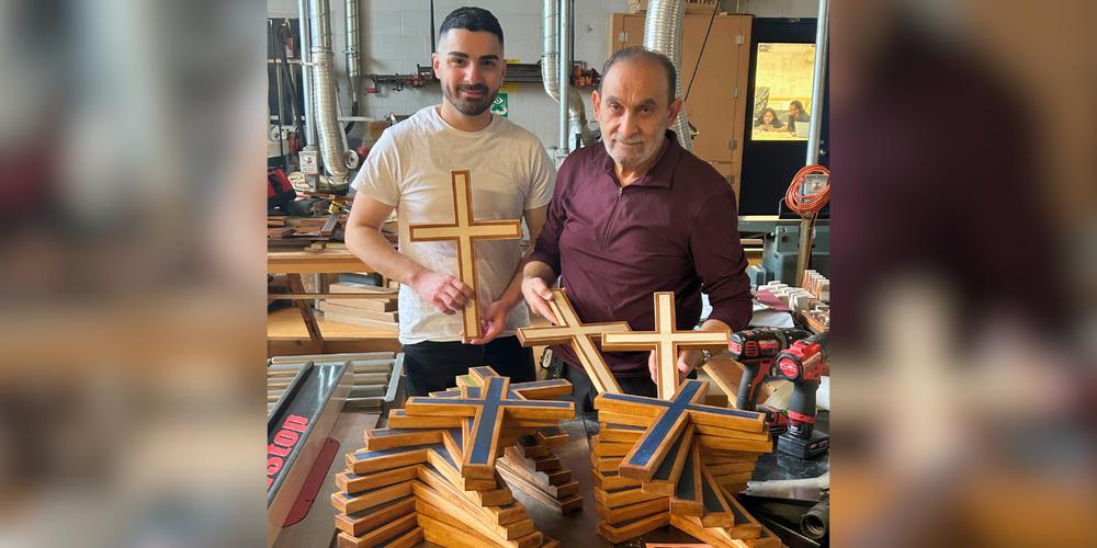 2 people holding crosses in front of a large amount of the same cross.
