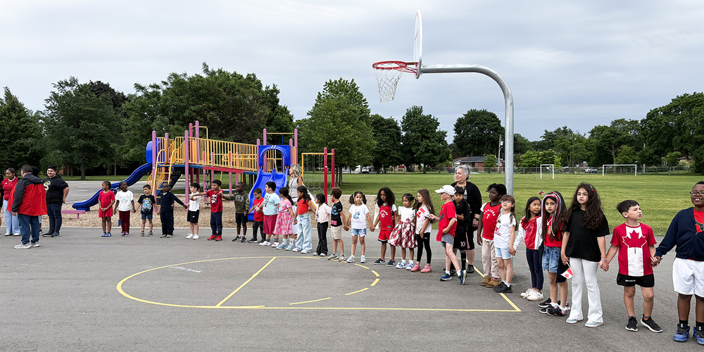 Photo of St. John Viannery students in the school grounds holding hands and wearing Canada shirts