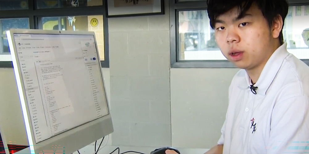 Photo of Nathan explaining his technology while in front of a computer terminal