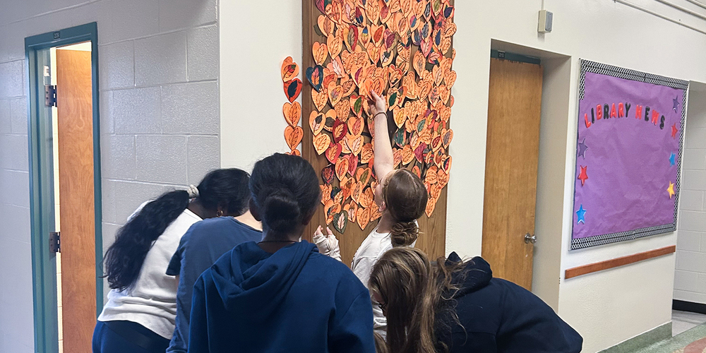 Photo of St. Cecilia students posting up hearts into the collaborative Tree of Life display